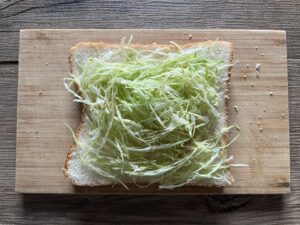 千切りキャベツを食パンにのせ塩こしょうする